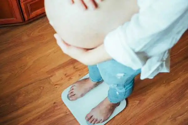 Image of woman weighing herself and experiencing weight gain through pregnancy Trowbridge